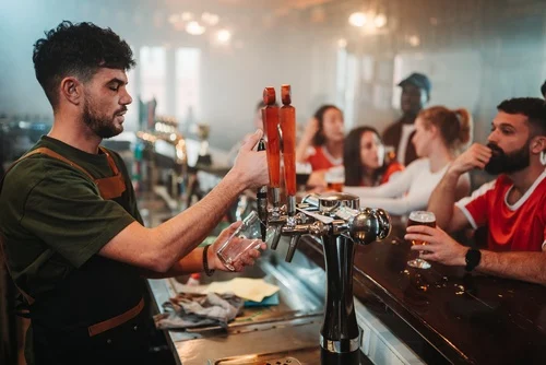 Camarero sirviendo una bebida de un grifo en un bar.
En España, para asegurar el cumplimiento del Estatuto de los Trabajadores, la edad mínima para puestos que implican la venta o el servicio de alcohol es de 18 años de edad.