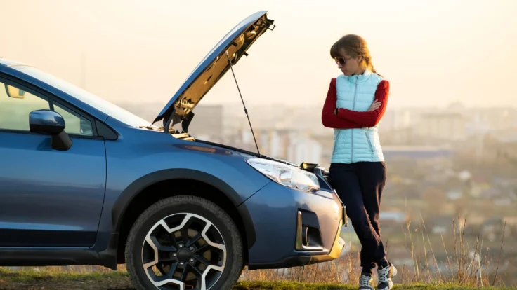 mujer mirando un coche averiado