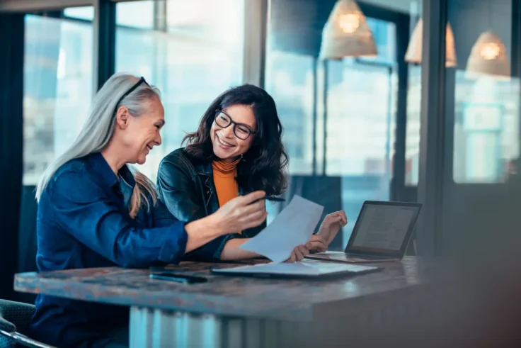Dos mujeres revisando y personalizando un currículum en una reunión profesional